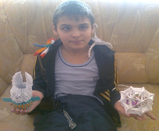 Мальчик показывает сделанную стрекозу, скорпиона, шар и зайчика